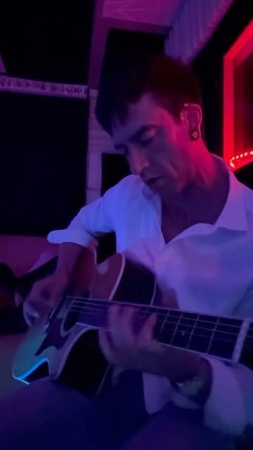Jasper playing acoustic guitar in a red-lit room
